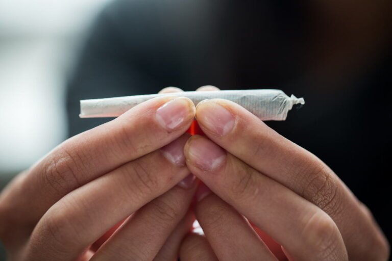 close up of addict hands with marijuana joint